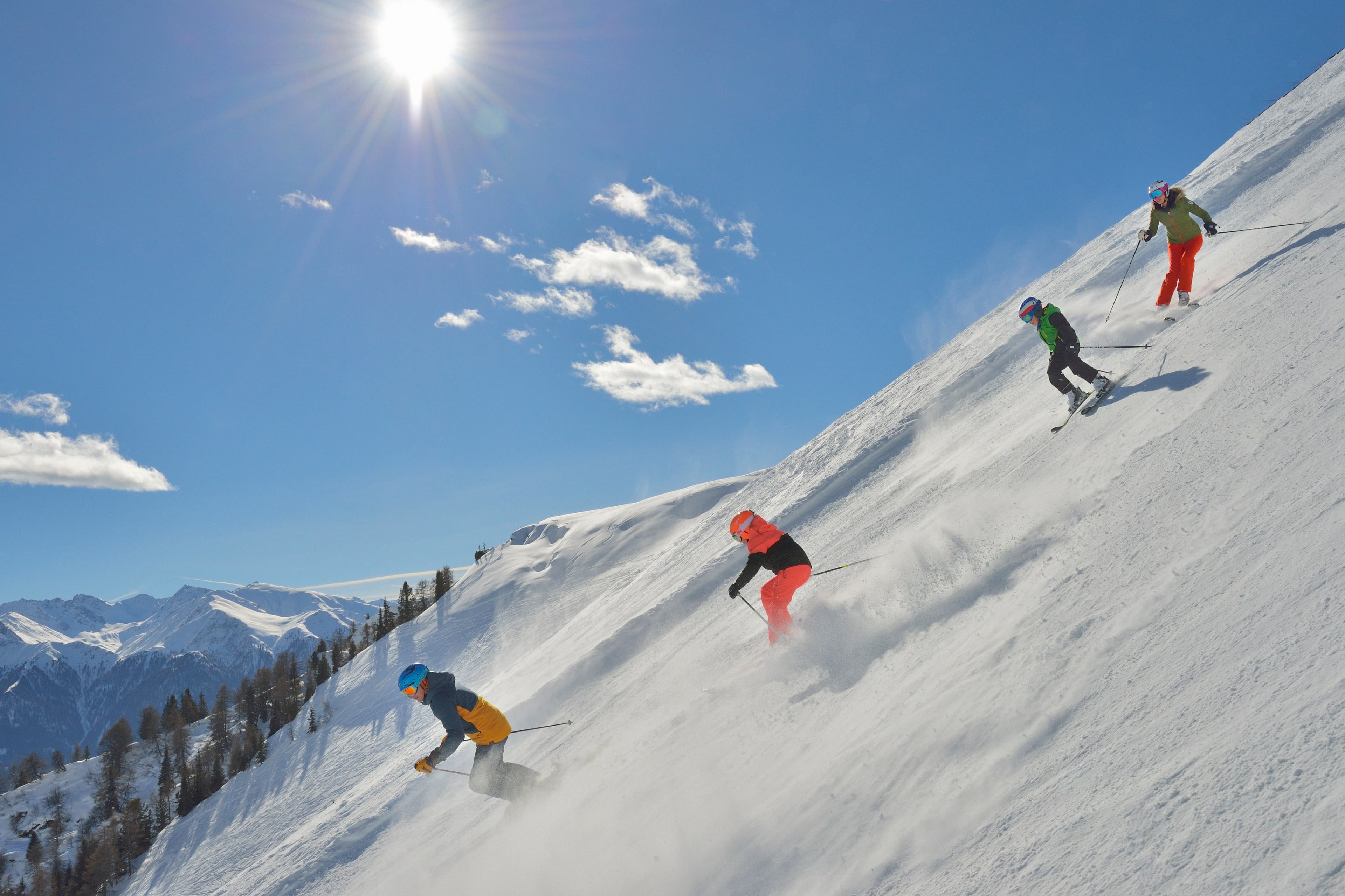 Family of skiiers skiing down steep ski slope in Austrian mountains